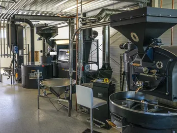 Roasting machines process coffee beans in a modern coffee roasting room.