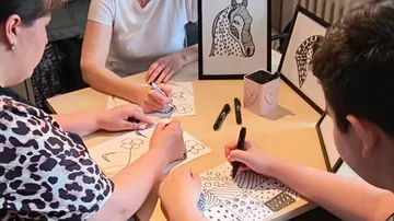People draw together on a table surrounded by pictures.