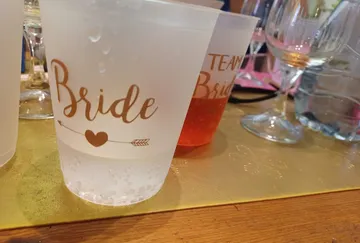 Durchsichtige Becher mit Aufschriften stehen auf einem Tisch.