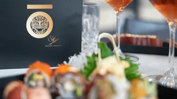 Sushi-Platte mit Getränken auf elegantem Tisch arrangiert.