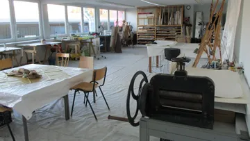 Workshop with tables, creative materials and printing press.