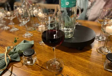 Red wine is sitting on a wooden table surrounded by glasses.