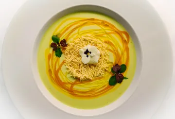 Creamy soup with cheese, flowers and green herbs.