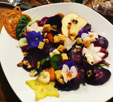 Colourful salad dish with vegetables, flowers and croutons.