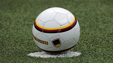 Ein Fußball liegt auf grünem Kunstrasen.