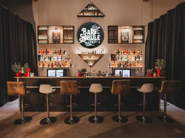 Modern bar with shelves full of spirits and chairs.