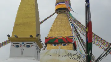 Stupa mit Fahnen, Vögel sitzen und fliegen darum.