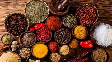A variety of spices in bowls on a wooden surface.