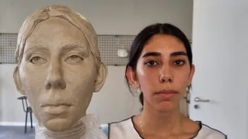 Sculpture of a head held by a person.