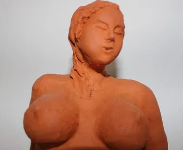 Clay figure depicts female form with relaxed facial expression.