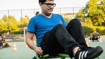 Young man drives a toy vehicle on the square.