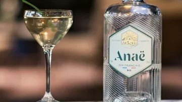 Ein Glas mit Gin steht neben einer Flasche Anae.