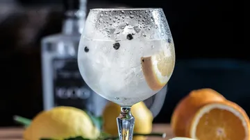 Glas mit Eis, Zitrone und Pfefferkörnern; kühlend, festlich.