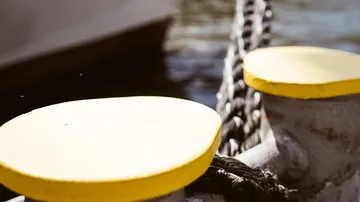 Yellow bollards hold a rope on the water.