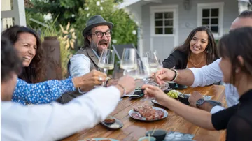Laughing people toast with glasses on a terrace.