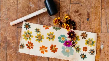 Floral pattern on fabric, next to it a hammer and flowers.