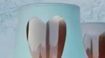 Two glasses with heart shapes stand in front of a blue wall.