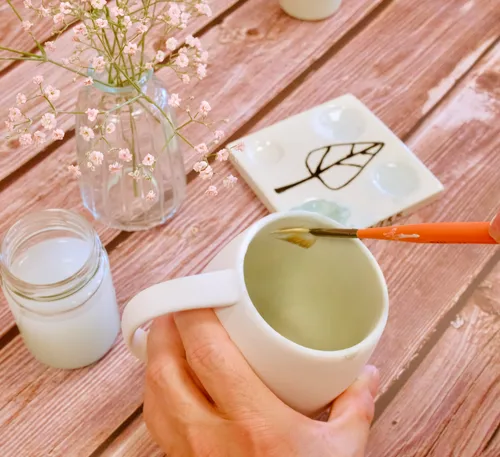 Tasse mit Pinsel färbt Innenraum, umgeben von Blumen.