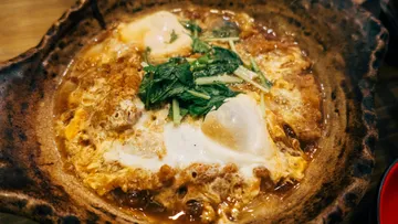 Eier in einer Brühe, garniert mit Kräutern und Zwiebeln.