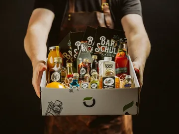 Cardboard with drinks is being held by someone.