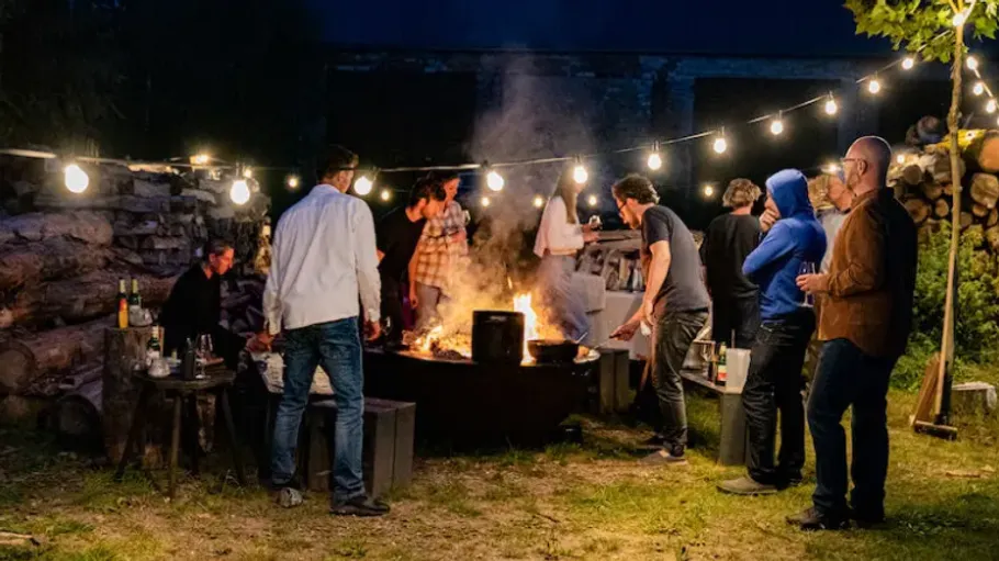 Gruppe von Menschen um ein Feuer im Freien.