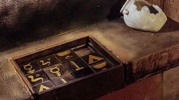 Schatztruhe mit mysteriösen Symbolen, neben einer zerbrochenen Tasse.
