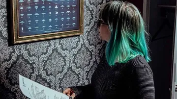 Woman with turquoise hair looks at a framed picture.