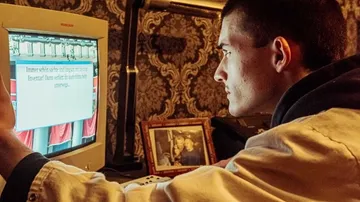 Mann tippt konzentriert an einem Computer in einem Raum.