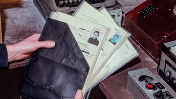 A man is holding a black folder with documents.