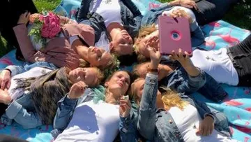 Group of women taking selfies in a meadow.