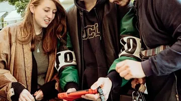Four people are looking at a smartphone together in a city.