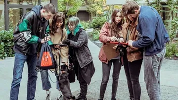 Six people interact with a dog while out and about.