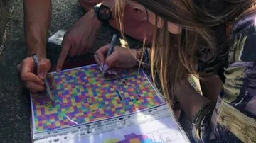 Colourful grids are edited by two people with pens.