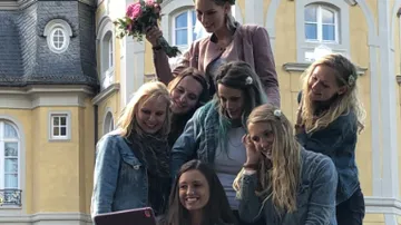 A group of women take a selfie in front of a building.