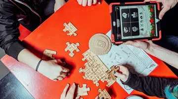 Puzzle und Tablet, Menschen spielen an einem Tisch.
