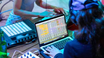 Laptop mit Musiksoftware, benutzt von Person in Kopfhörern.