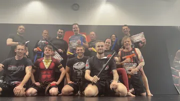 Group of people posing with exercise equipment in a room.