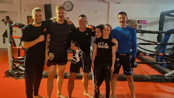 Six people smile happily in a martial arts studio.