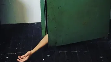 Grüne Tür öffnet sich, Hand liegt am Boden.