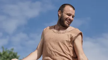 Smiling man in simple clothes under blue sky.