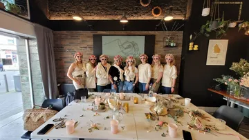 Gruppierte Frauen mit Blumenkränzen posieren in einem stilvollen Raum.