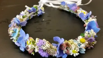 Blumenkranz aus bunten Blumen liegt auf schwarzem Untergrund.