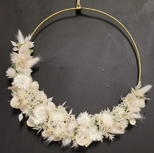 Blumenkranz mit weißen Blumen auf schwarzer Wand.