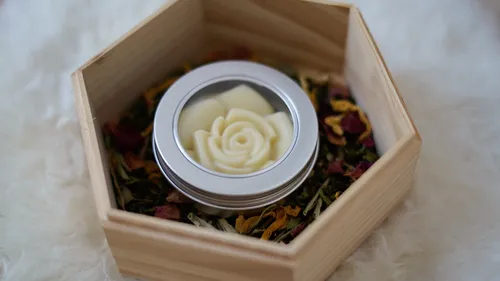 A round container with a rose shape in a wooden box.