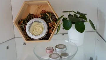 Wooden box with dried flowers and scented candle, plant next to it.