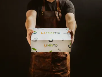 A person holds out a package with the text “LI.MIN.TO”