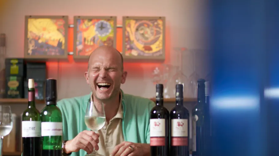 Man laughs happily while holding a wine glass.