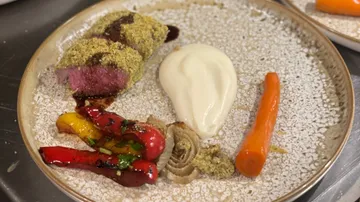 Ein kunstvoll angerichteter Teller mit Fleisch und Gemüse.