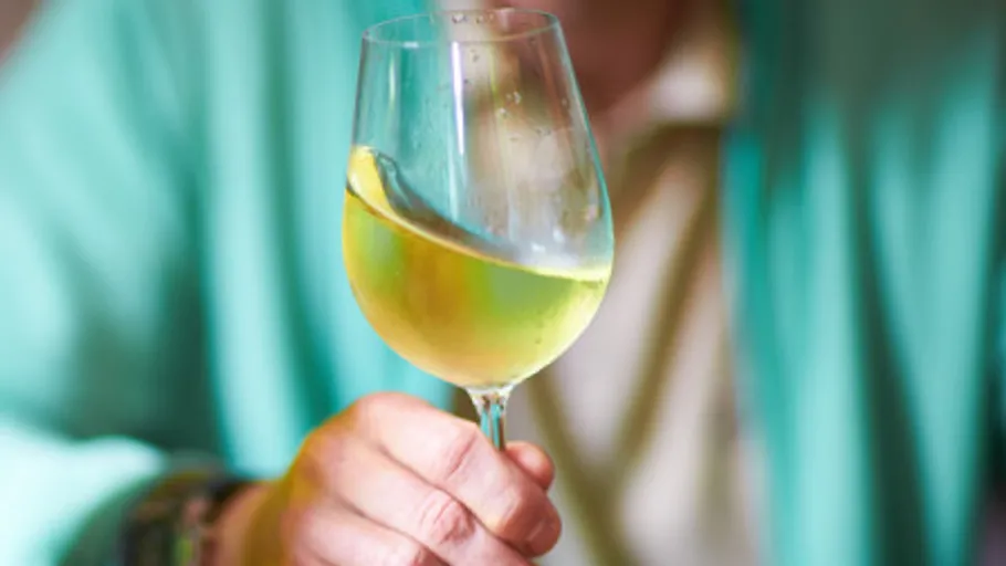 Ein Glas Wein wird mit einer Hand gehalten.