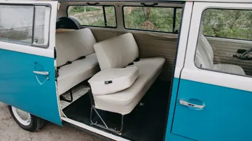 Blauer VW-Bus mit weißen Sitzen, offen für Insassen.